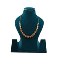 Handcrafted Lalithambike 1-gram gold beaded necklace with intricate ruby-toned filigree work and cream pearl accents on a teal jewelry bust.