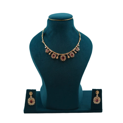 Lalithambike 1-gram gold floral choker featuring rectangular ruby-toned stones and delicate gold petals with matching statement earrings on a teal jewelry bust.
