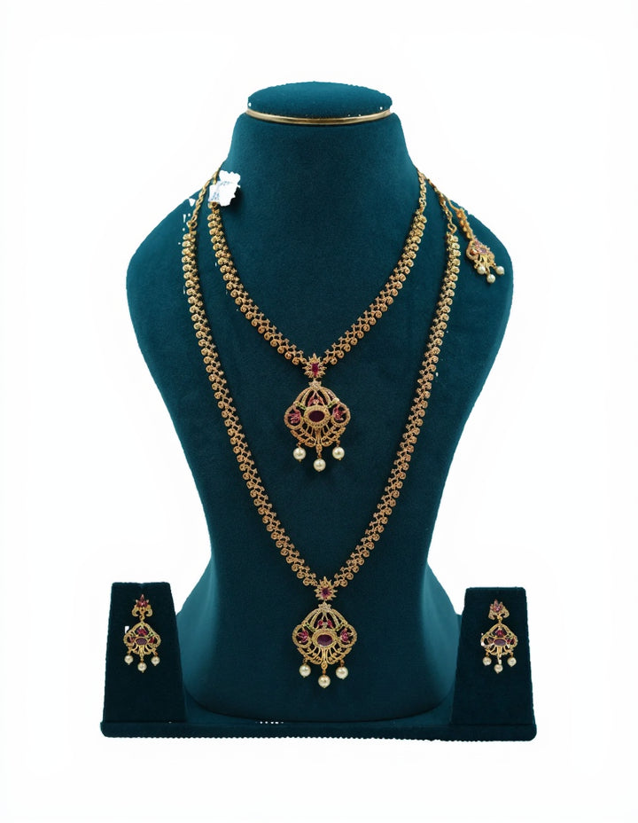Lalithambike 1-gram gold bridal combo set featuring a short necklace, long haram, maang tikka, and ruby-accented earrings on a teal display.