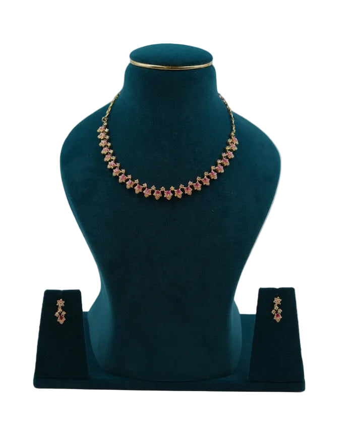 Handcrafted Lalithambike 1-gram gold star-motif choker necklace featuring vibrant ruby-toned center stones and matching floral drop earrings on a teal jewelry bust.