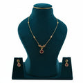 Lalithambike delicate 1-gram gold chain featuring ruby and emerald teardrop pendant with matching earrings on a teal jewelry bust.